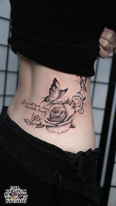 a woman's stomach with a rose tattoo on her lower side ribcage