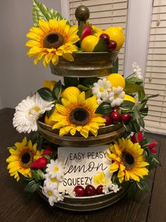 a three tiered cake decorated with sunflowers, cherries and lemons