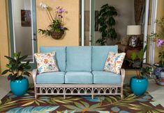 a blue couch sitting on top of a rug next to two potted planters