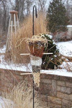 a tall bird feeder sitting on top of a metal pole next to snow covered ground