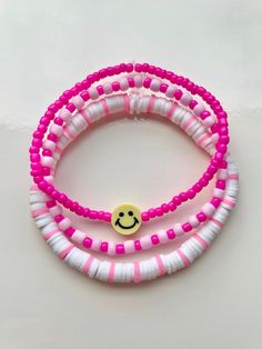 two pink and white bracelets with smiley face charms on each beaded strander