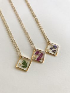 three different necklaces with flowers on them