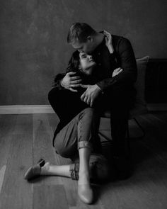 a man and woman sitting on the floor in black and white with their arms around each other