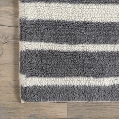 a gray and white rug on top of a wooden floor next to a wood floor