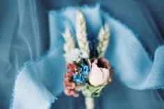 a bouquet of flowers is wrapped in blue fabric and placed on a bed sheet or table cloth