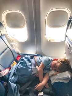 a little boy sleeping on an airplane seat