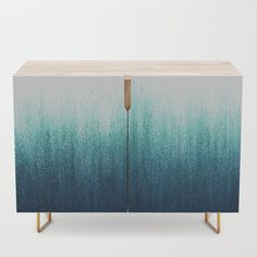 a blue and green cabinet with gold legs