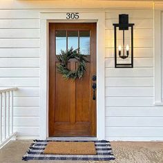 a front door with a wreath on it and two lights hanging from the side wall