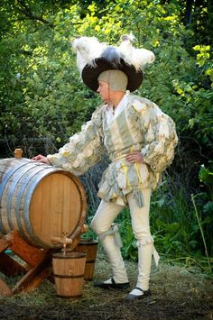 a man dressed in period clothing standing next to a barrel