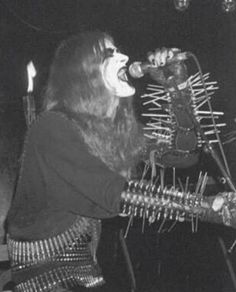 a man with long hair holding a microphone in his mouth while standing next to a guitar