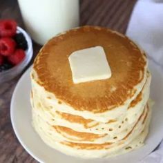 a stack of pancakes with butter and berries on the side