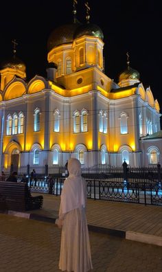 a nun in front of a large building lit up at night with lights on it