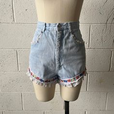 These 1990's vintage Extra Femme shorts are made from a light washed, cotton denim and white, nylon lace. Features a high waisted fit with floral ribbon around either leg and white, ruffled lace trim. Zips in front to a single button closure at the waist. A couple small tears in the lace that aren't noticeable but reflected in price. In overall excellent vintage condition with only minimal signs of wash and wear.   Marked a size 7, see below for measurements 25" waist 36" hips 13" rise 3" inseam Vintage Jeans With Frayed Hem For Spring, Spring Vintage Jeans With Frayed Hem, Vintage Denim Blue Jeans For Summer, Vintage Denim Jean Shorts For Summer, Fitted Denim Bottoms With Lace Trim, Summer Denim Bottoms With Lace Trim, Denim Bottoms With Lace Trim For Summer, Light Wash Cotton Jean Shorts For Spring, Spring Light Wash Cotton Jean Shorts