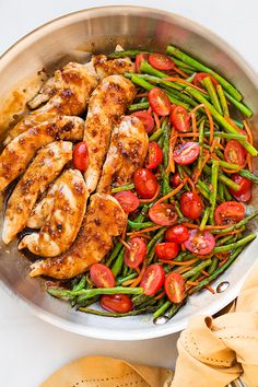 a pan filled with chicken, green beans and tomatoes