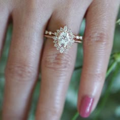 a woman's hand with a diamond ring on it and flowers in the background