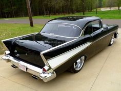 an old black and white car is parked in the driveway