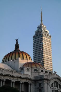 the top of a building with a statue on it's roof and a tall skyscraper in the background