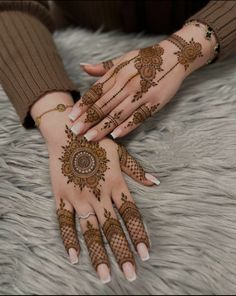 two hands with henna tattoos on them