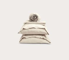 three pillows stacked on top of each other in front of a white wall with a rose