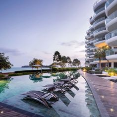 an outdoor swimming pool with lounge chairs next to it