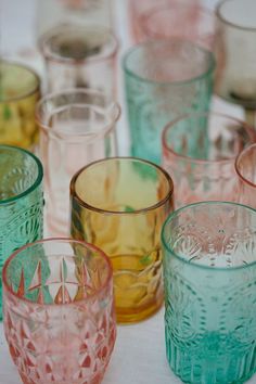 several different colored glasses sitting on top of a table next to each other and one is empty