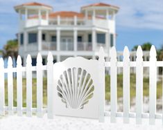 a white picket fence with a shell logo on it and a house in the background