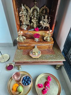 there are plates and bowls on the floor next to an ornate shrine with candles in it