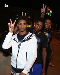 three young men standing next to each other with their hands in the air