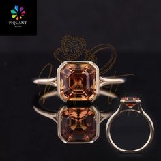 a ring with an orange topazte surrounded by two smaller diamonds on a black background