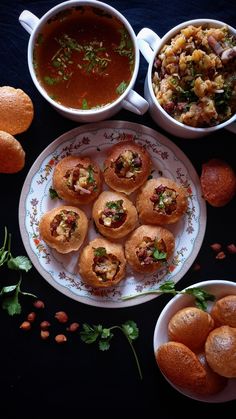 some food is sitting on a plate next to bowls of soup and other foods that include bread