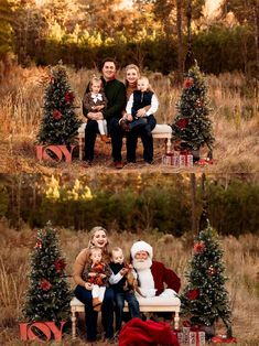 a family sitting on a bench in front of christmas trees