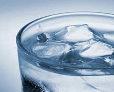 a glass filled with ice and water on top of a table