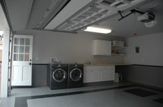 a washer and dryer are in the middle of a large room with white cabinets