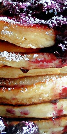 a stack of blueberry pancakes with powdered sugar on top and syrup drizzled over them