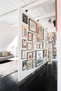 a living room filled with lots of pictures on the wall next to bookshelves