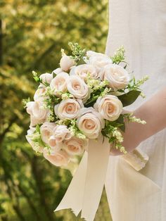 a bride holding a bouquet of white roses