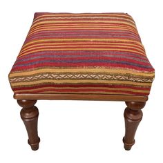 a wooden foot stool with a multi colored striped cushion on the top and legs, against a white background