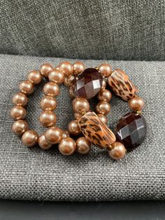 Set of 3 bronze colored beaded bracelets with brown and cheetah print beads. Inner diameter 3 inches. Stretch good. Cheap Brown Bracelet Jewelry, Luxury Elegant Brown Beads, Cheap Brown Jewelry With Gold Beads, Luxury Brown Round Bead Bracelets, Brown Beaded Stretch Bracelet With Round Beads, Elegant Brown Bracelets With Large Beads, Brown Bracelet With Gold Beads, Brown Stretch Bracelet With Faceted Beads, Adjustable, Adjustable Brown Stretch Bracelet With Faceted Beads