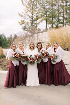 the bride and her bridesmaids are all dressed in burgundy dresses with fur stoles