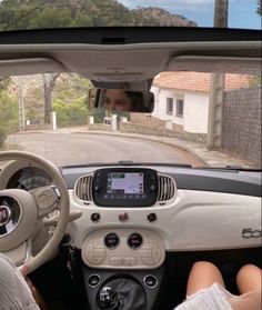 two people are sitting in the driver's seat of a small car, looking at their cell phone