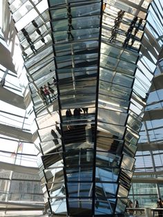 people are standing on the glass walkway inside an office building