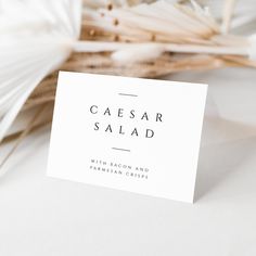 a white business card sitting on top of a table next to some sticks and flowers