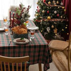 a table set for christmas dinner next to a christmas tree