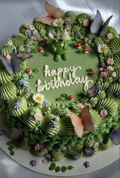 a green birthday cake decorated with flowers and butterflies