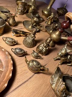 a table topped with lots of brass figurines on top of a wooden table