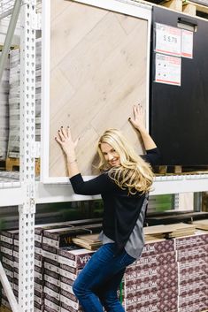 a woman is standing in front of a large piece of wood with her hands up