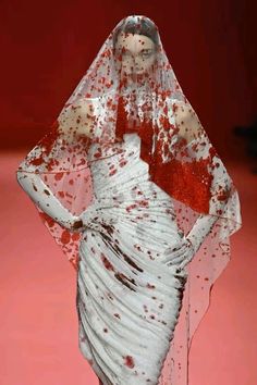 a white dress with red splatters on it and a veil over its head