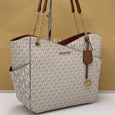 Michael Kors Jet Set Large Logo Shoulder Bag Shoulder Bag Vanilla Signature Logo-Print Canvas 89.4% Coated Canvas/9.6% Polyester/1% Polyurethane Gold-Tone Hardware 15.6”W X 11”H X 5.5”D Handle Drop: 10" Exterior Details: Front Slip Pocket Interior Details: Back Zip Pocket, 2 Back Slip Pockets Lining: 100% Polyester Zip Fastening Imported Michael Kors Large Capacity Shoulder Bag, Michael Kors Beige Shoulder Bag With Gold-tone Hardware, Luxury Michael Kors Shoulder Bag With Gold-tone Hardware, Michael Kors Coated Canvas Shoulder Bag With Gold-tone Hardware, Grey Shoulder Bag, Michael Kors Leather Shoulder Bag With Silver-tone Hardware, Mk Purse, Leather Harness, Michael Kors Shoulder Bag