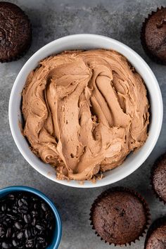 a bowl filled with chocolate cupcakes next to two muffins on a table