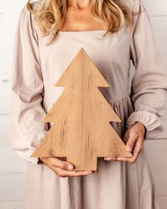 a woman holding a wooden christmas tree in her hands